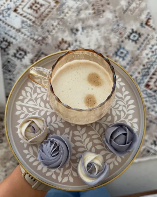 Plavi i bijeli mafini-ruže na ukrasnom tanjiru uz šoljicu kafe